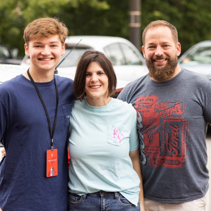 Mom and dad posing with college son