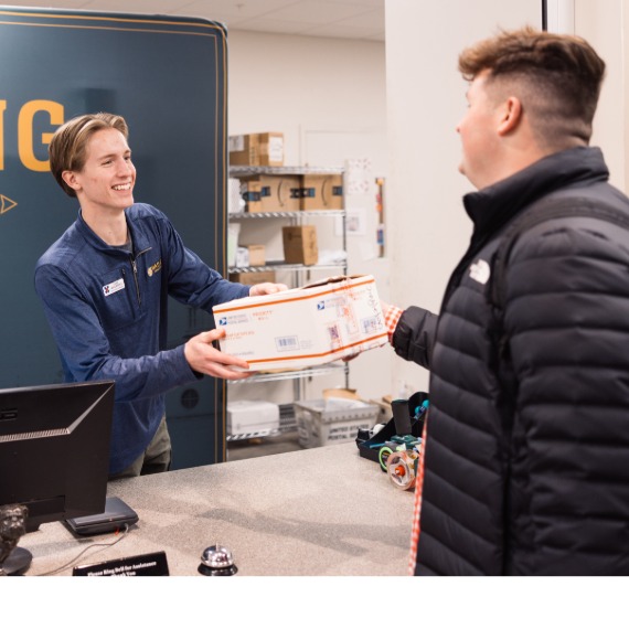 Mailing services associate giving man a package
