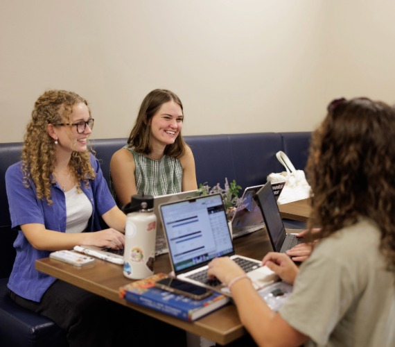 Women talking at table with laptops