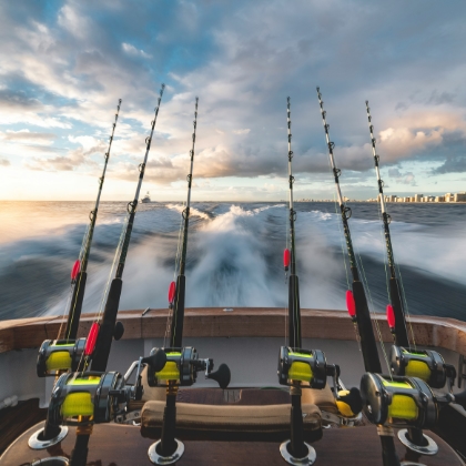 A photo of 4 fishing poles extended off the back of a boat moving through the water