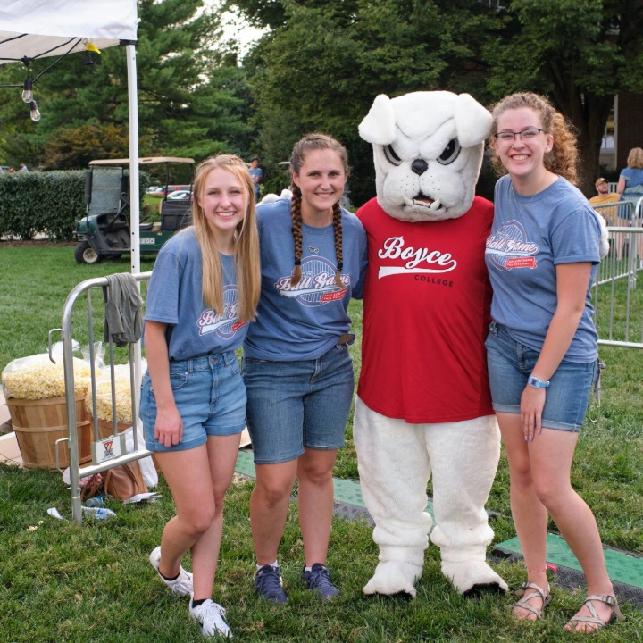 Three college students posting with Boyce bulldogs mascot