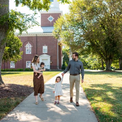 Husband, wife, and two small children walking on campus sidewalk