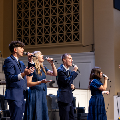 Vocalist singing into microphone with band members behind her